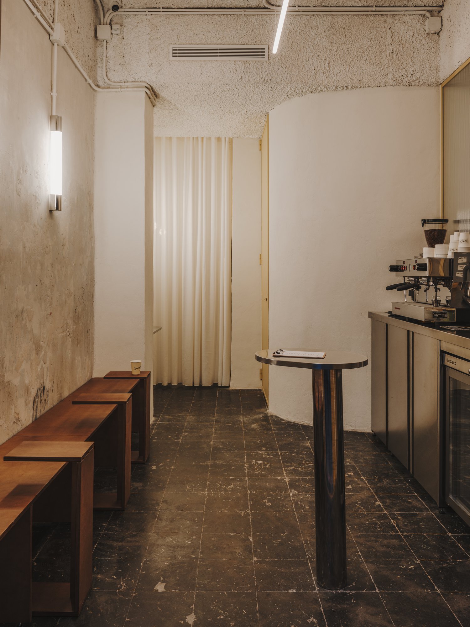 Zona de take away con bancos de contrachapado y suelo negro original