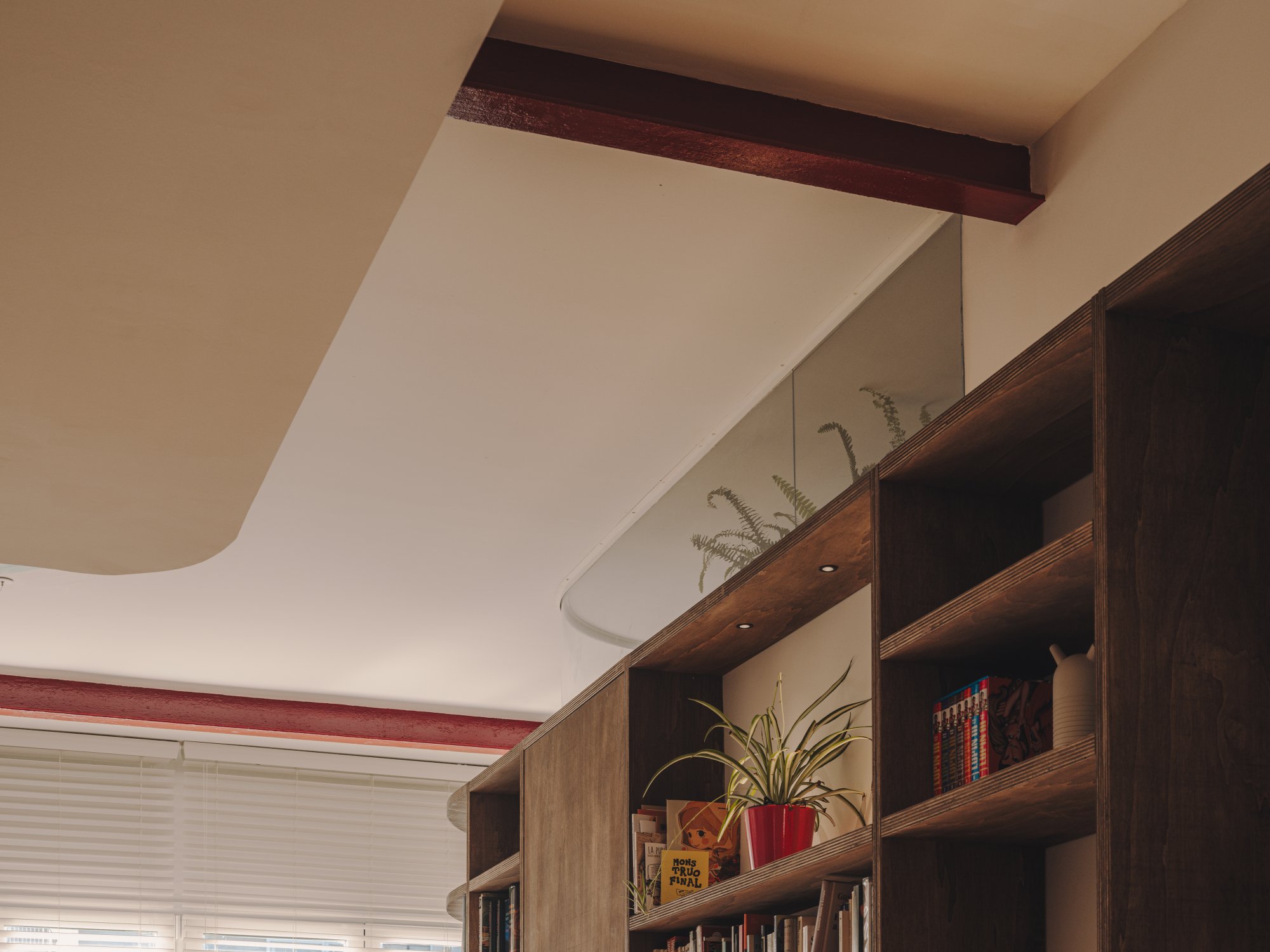 Viga vista y estantería curva bajo el techo de Casa Artista