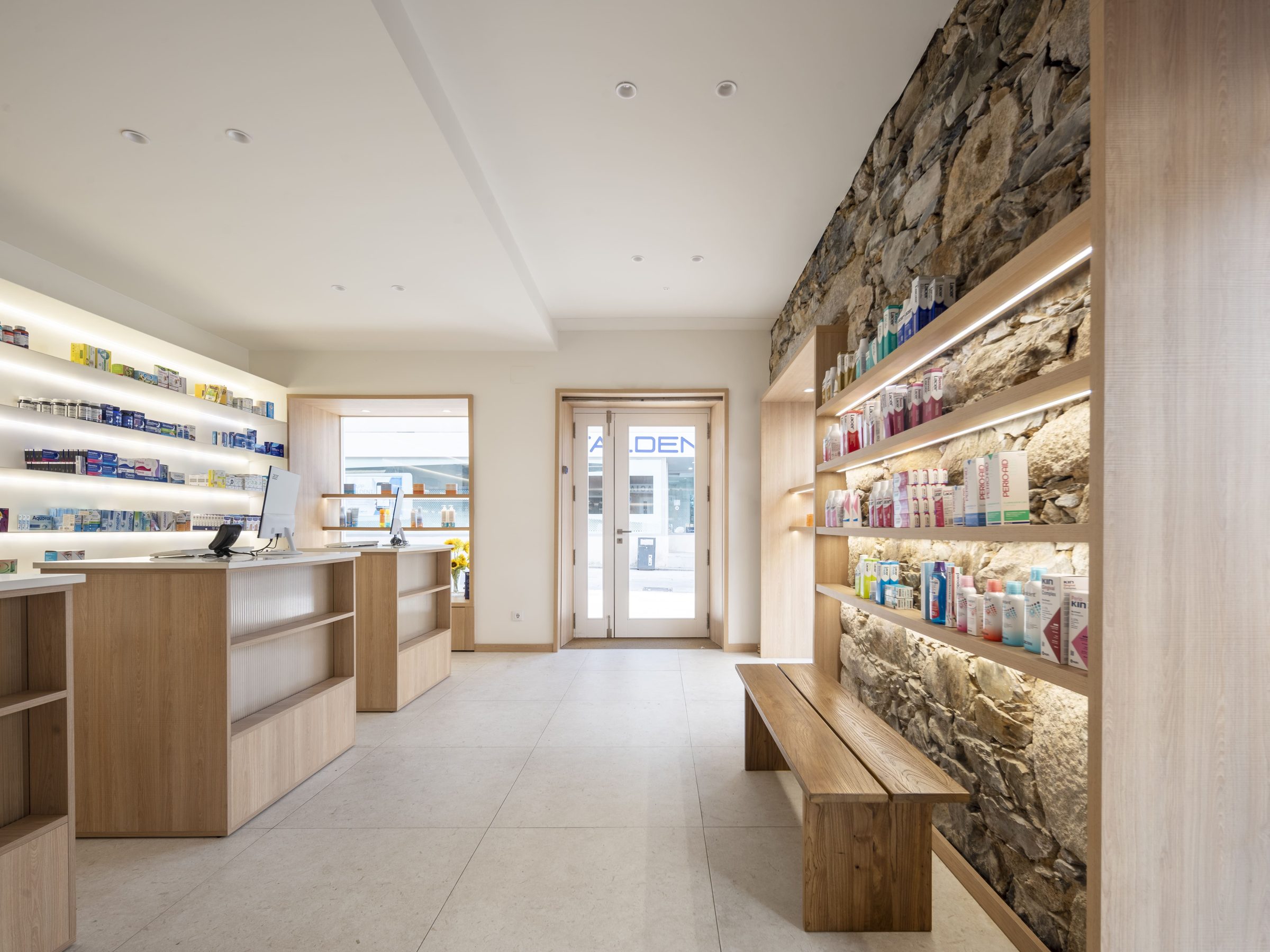Interior de Farmacia Real 101 con muro de piedra y mostradores de madera