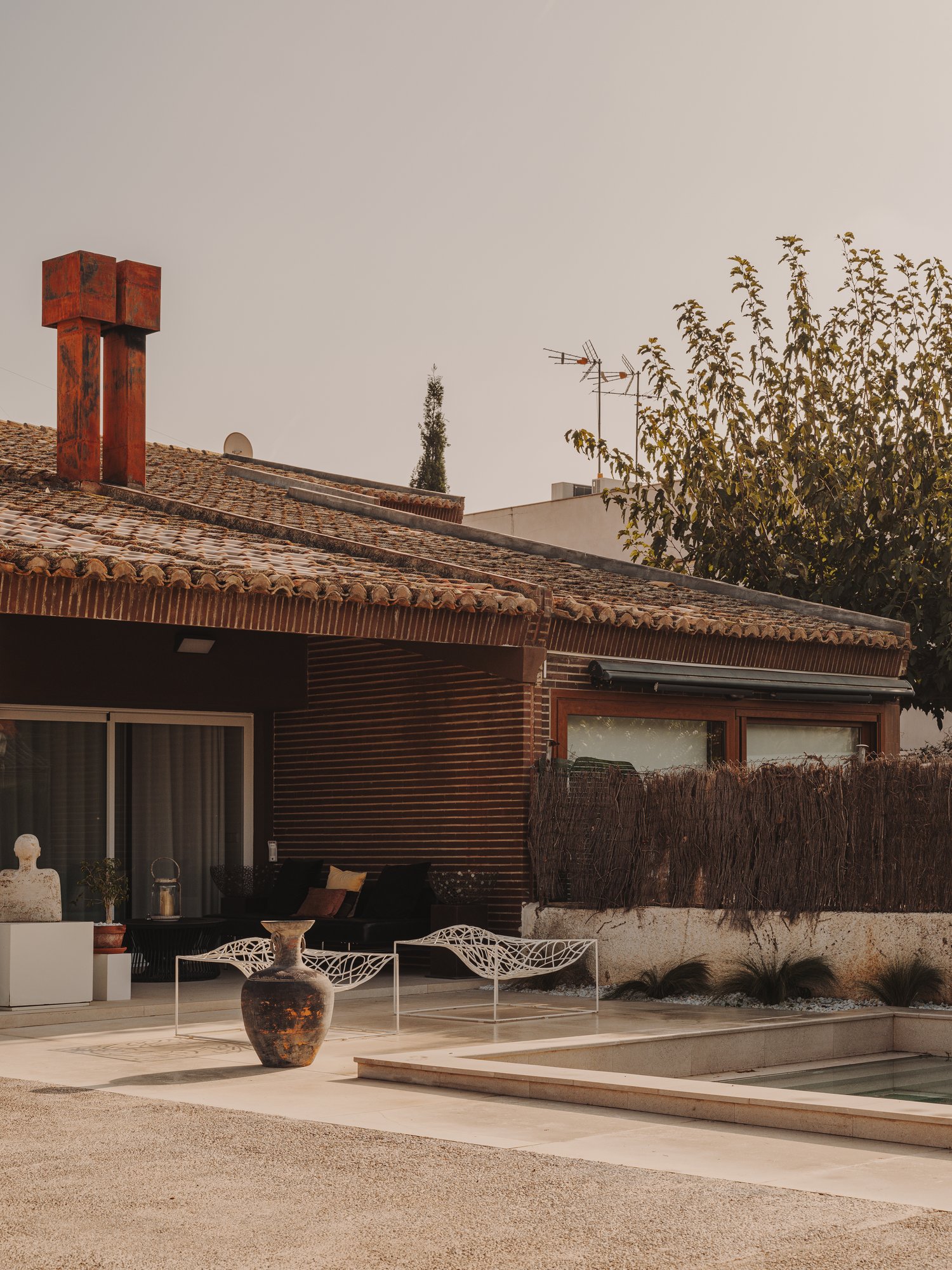 Fachada de ladrillo con la terraza y piscina